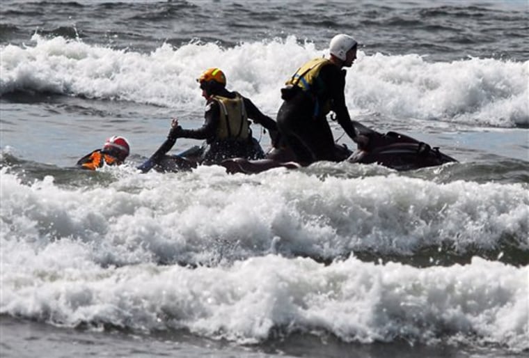 Surf rescue swimmers Eddie Mendez and Will Green pull Dale Ostrander aboard their jet ski after finding him in the surf off the Cranberry Road beach approach Friday, Aug. 5, 2011, in Long Beach, Wash. The boy was under water for up to 20 minutes, and is now hospitalized and conscious. (AP Photo/Chinook Observer, Damian Mulinix)